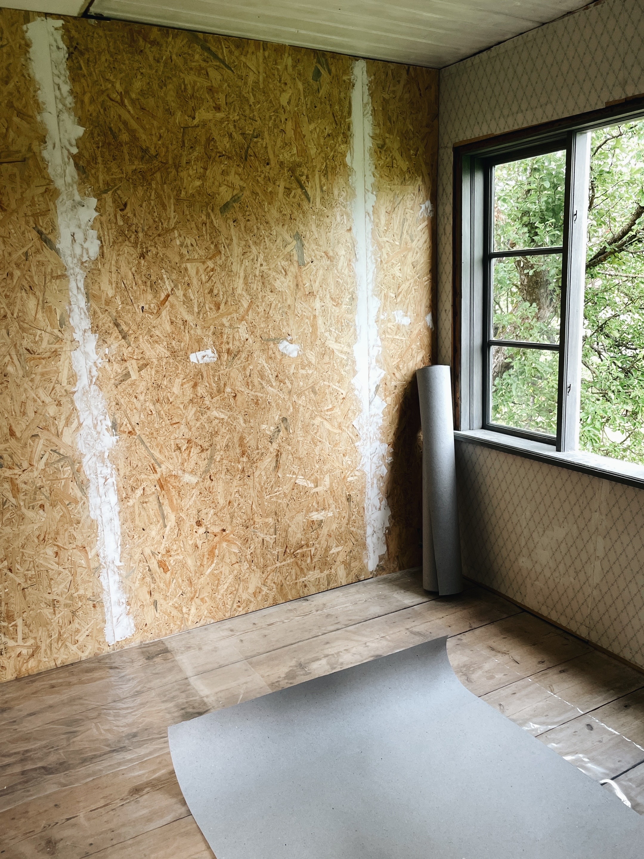 OSB-vägg med lumppappsrulle lutad i hörnet